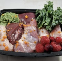 a black container with meat, berries, and kale