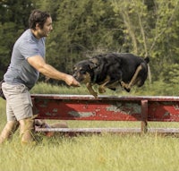 a man jumping over a bench with a dog