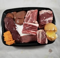 a black tray containing meat, eggs and cheese